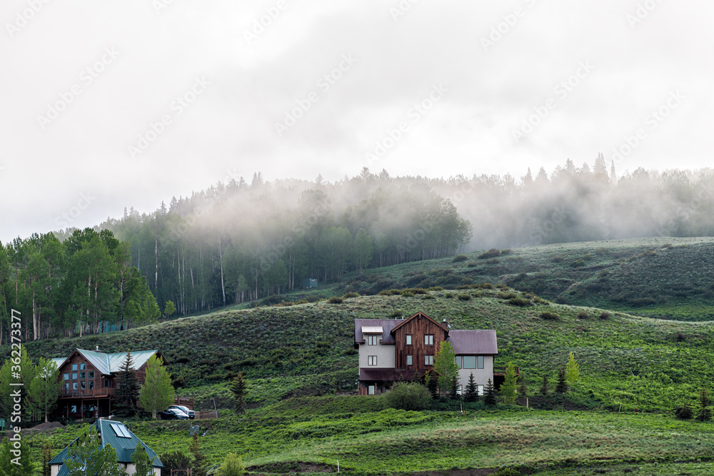 Obraz premium Crested Butte, USA Colorado small America town village in summer with clouds and foggy mist morning and houses on hillside with green trees