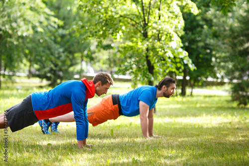 Two men doing pushups outdoor. Selective focus.