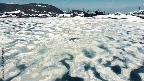 Stunning Aerial Drone view of frozen lake. Flying over lake covered with pieces of melting ice during the spring. photo