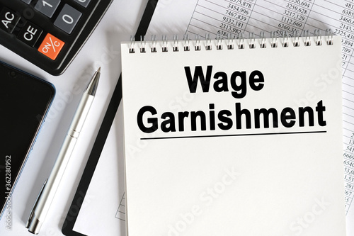 Картината върху платно On the table lies a smartphone, a calculator and a notebook with the inscription- Wage Garnishment