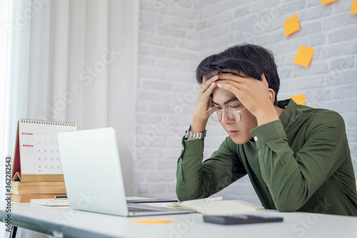 Foto Feeling tired. Young asian businessman feeling stress from work.