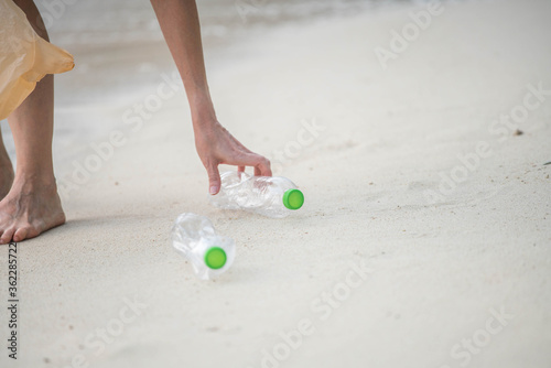 Woman walking garbage on plastic bottles on the beach