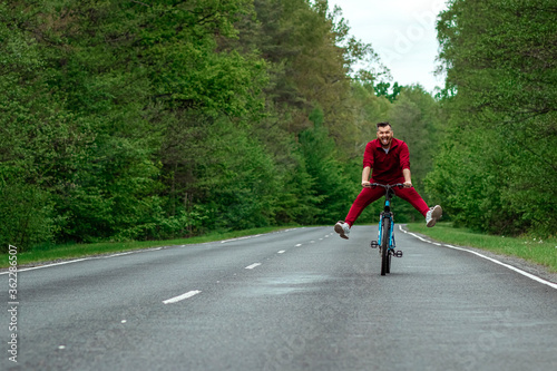 Wallpaper Mural Happy male riding bike with legs up. The road in the forest. The concept of a healthy lifestyle, cardio training. Copyspace. Torontodigital.ca