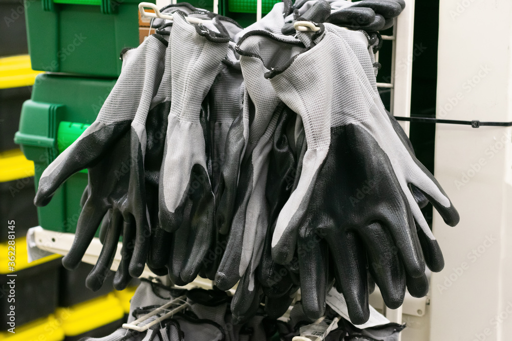 Rubberized grey work gloves hanging on the wall. Part of work-wear and protection equipment.