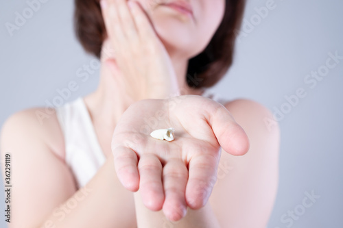 Wisdom tooth extraction  woman suffering from a toothache on gray background