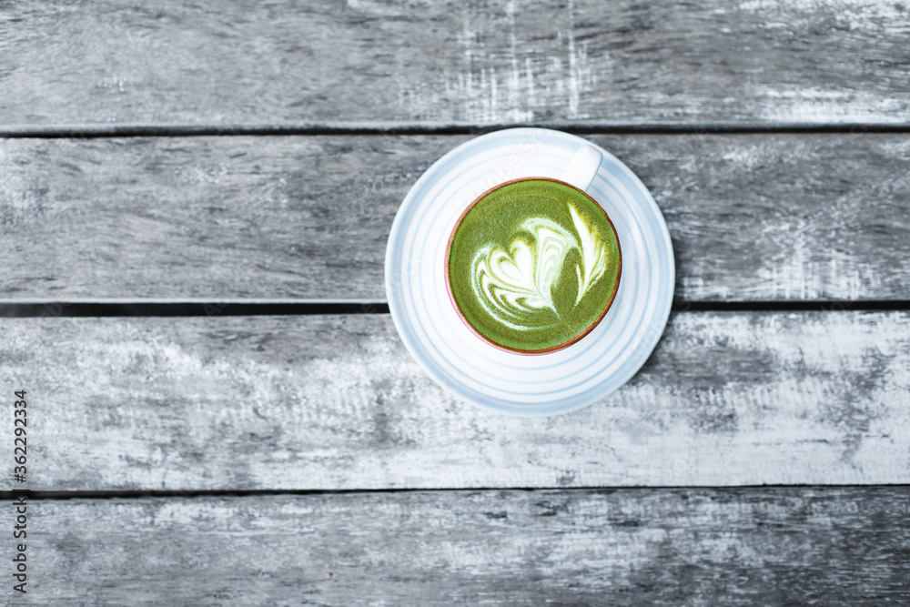 Cup of fresh green matcha latte beverage with latte art on foam. Background of wooden table with gray shabby aged surface. View from above. Healthy drink. Cup of fresh green matcha latte beverage with latte art on foam. Background of wooden table with gray shabby aged surface. View from above. Healthy drink.