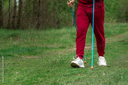 Nordic walking, sticks, legs close-up. The concept of a healthy lifestyle, cardio training. Copyspace.