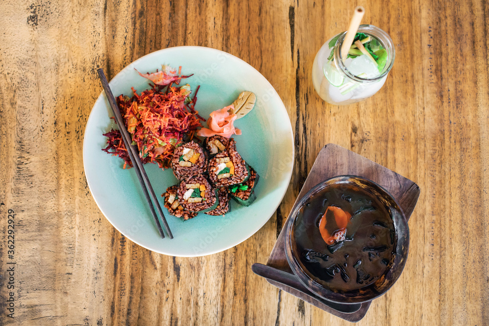 Vegetarian red rice sushi set with vegetable salad, tofu, tempeh, seaweed soup and lemonade. Vegan lifestyle and healthy food. Raw meal. Vegetarian red rice sushi set with vegetable salad, tofu, tempeh, seaweed soup and lemonade. Vegan lifestyle and healthy food. Raw meal.