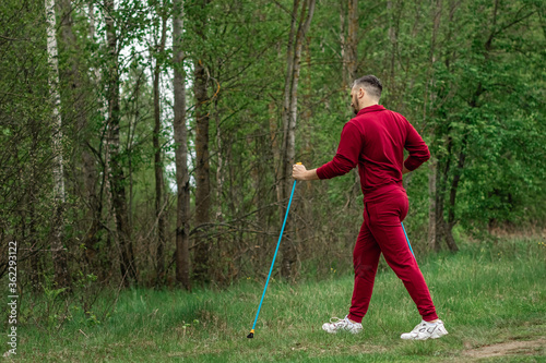 A man in a tracksuit is engaged in Nordic walking. The concept of a healthy lifestyle, cardio training. Copyspace.