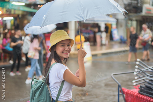 Photography Young Asian woman holding umbrella walking in the street.