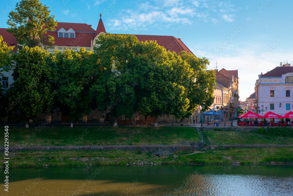 Obraz premium UZHHOROD, UKRAINE - JUN 04, 2017. beautiful sunny morning in uzhgorod. embankment of the river uzh in summertime