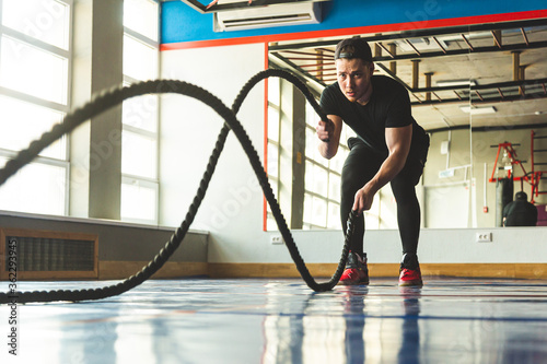 Crossfit in the gym with ropes. The athlete is training.
