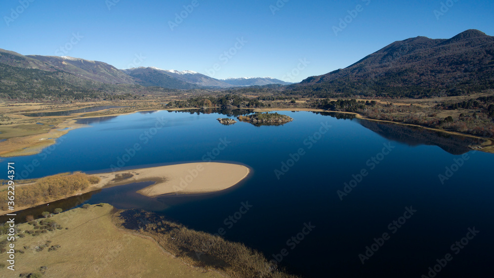 Aerial view of the fresh blue water lake in the mountains, the valley, meadow and forest, in a sunny summer day. 