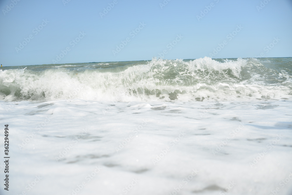 average waves on the sea reach the shore with foam and crash on the rocks with a noise