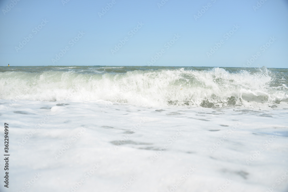 average waves on the sea reach the shore with foam and crash on the rocks with a noise average waves on the sea reach the shore with foam and crash on the rocks with a noise