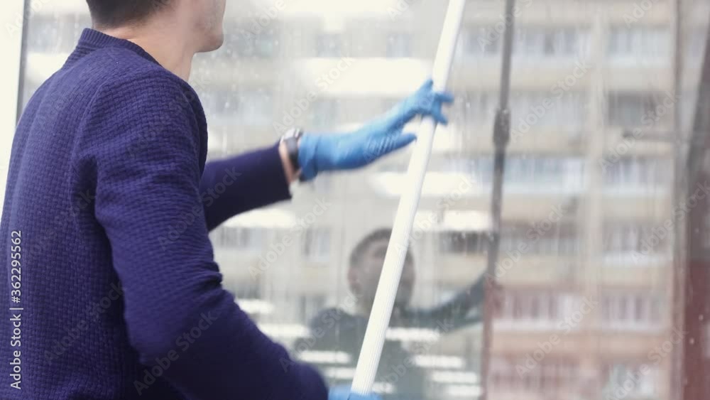 a professional window cleaner soaps and squeegies a window clean, male cleaning worker. a professional window cleaner soaps and squeegies a window clean, male cleaning worker.