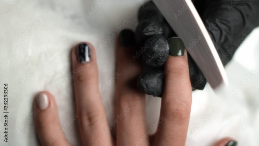 Manicurist carefully filing down the edges of a clients nails after they have been polished Manicurist carefully filing down the edges of a clients nails after they have been polished