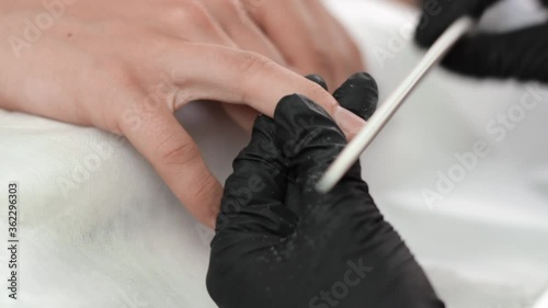 Manicurist using an emery board to file down the edges of a clients nails photo