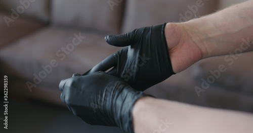 man hands takes off black nitrile protective gloves indoors