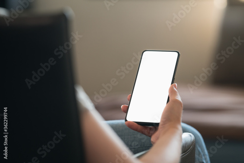 Young woman sitting in chair with modern smartphone with white screen