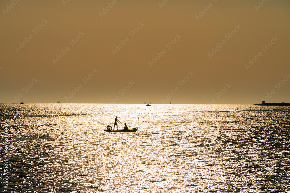 Fototapeta premium man in a boat backlight with reflections on the mediterranean sea