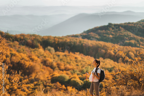 Wallpaper Mural Pregnant woman nordic walking with trekking sticks on hill with beautiful autumn mountain view. Pregnancy activity and healthy lifestyle in maternity time. Travel concept. Torontodigital.ca