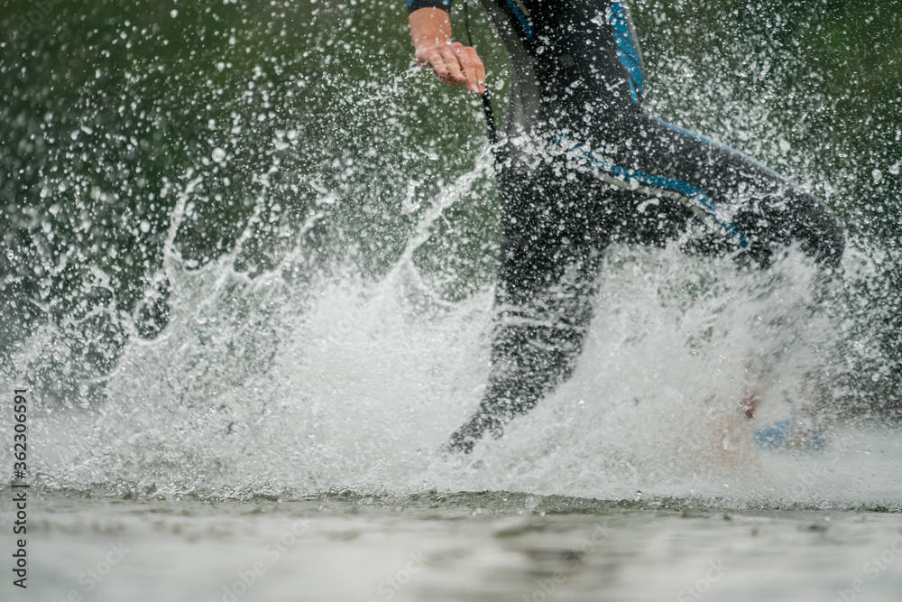 Triathlete in a wetsuit running into the lake Triathlete in a wetsuit running into the lake