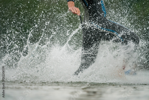 Triathlete in a wetsuit running into the lake
