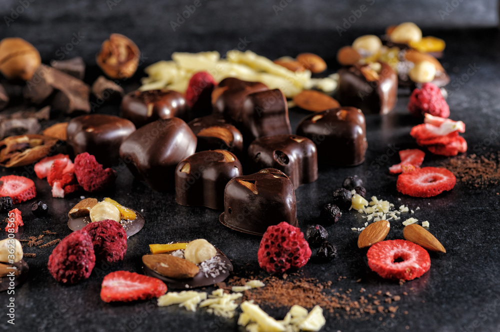 black chocolate with handmade freeze dried berries and nuts, natural on a dark background, top view