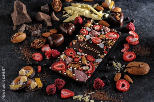 black chocolate with handmade freeze dried berries and nuts, natural on a dark background, top view