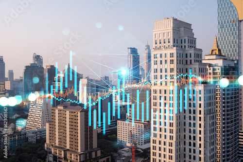 Glowing FOREX graph hologram, aerial panoramic cityscape of Bangkok at sunset. Stock and bond trading in Asia. The concept of fund management. Double exposure.