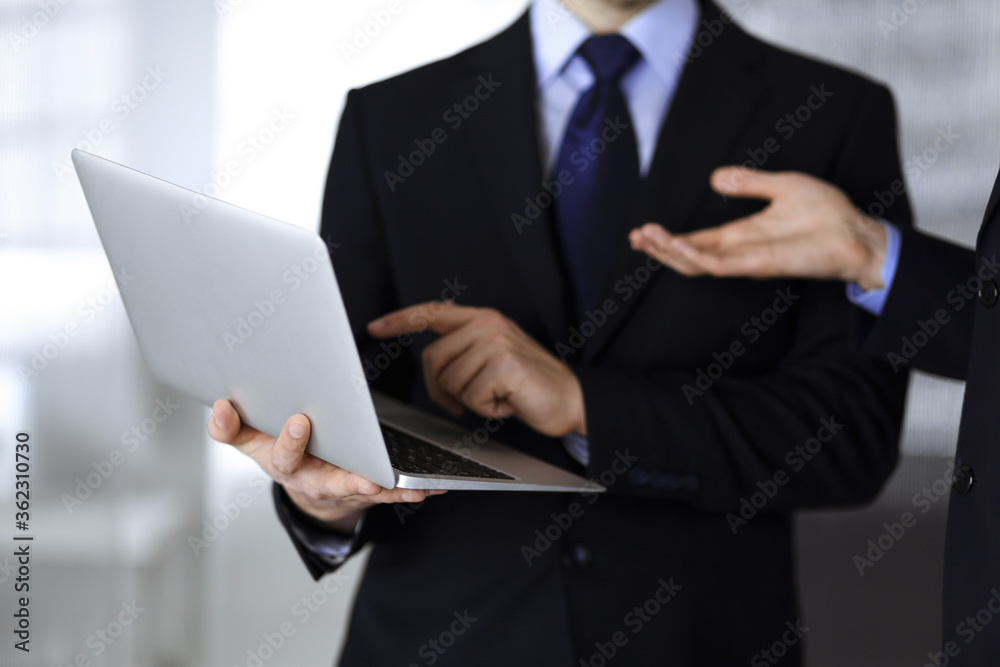 Business people discussing a presentation at meeting, standing in a modern office. Unknown businessman with a colleague search for some information at the laptop, lawyers at negotiation. Teamwork and Business people discussing a presentation at meeting, standing in a modern office. Unknown businessman with a colleague search for some information at the laptop, lawyers at negotiation. Teamwork and