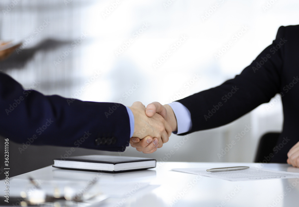 Business people shaking hands at meeting or negotiation, close-up. Group of unknown businessmen in a modern office. Teamwork, partnership and handshake concept
