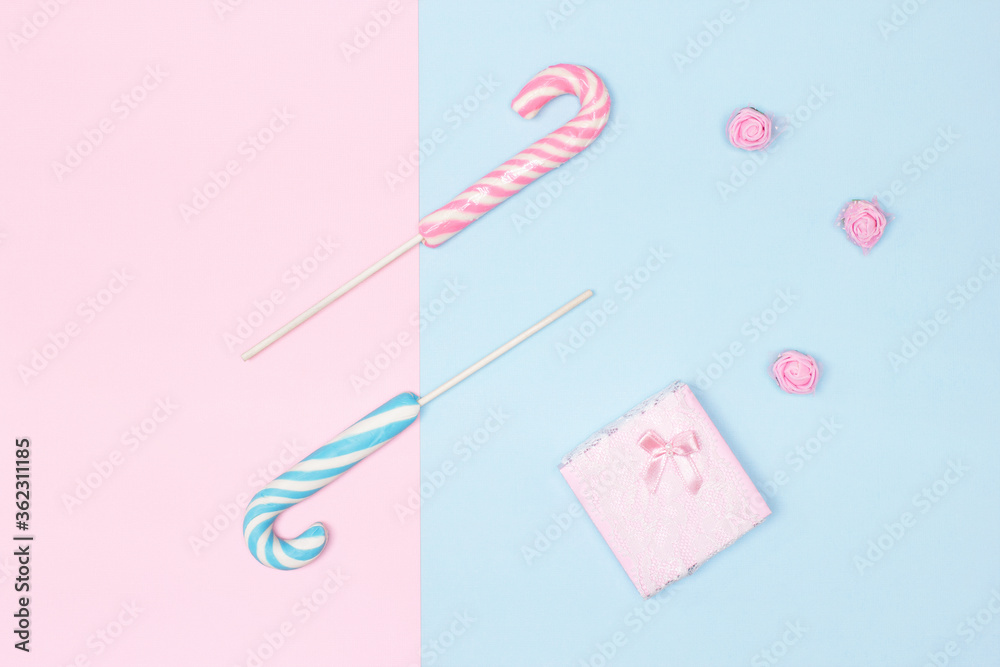 Two candy canes with gift box on pastel blue and pink background. Top view, flat lay. Congratulation feminine minimal concept Two candy canes with gift box on pastel blue and pink background. Top view, flat lay. Congratulation feminine minimal concept