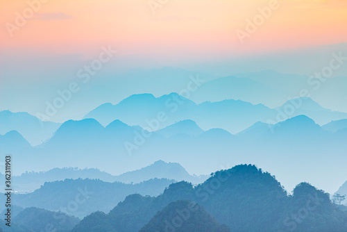 Ha Giang karst geopark landscape in North Vietnam. Mountain silhouette stunning scenery mist and fog in the valleys at sunset. Ha Giang motorbike loop, famous travel destination bikers easy riders.