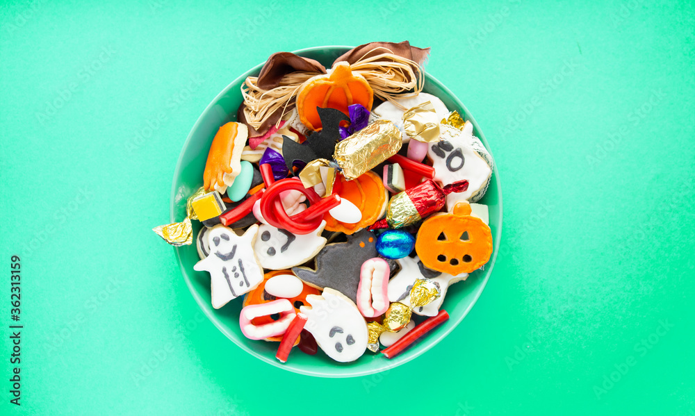 Halloween Jack o Lantern candy bowl with candy and halloween cookies Trick or Treat on green background