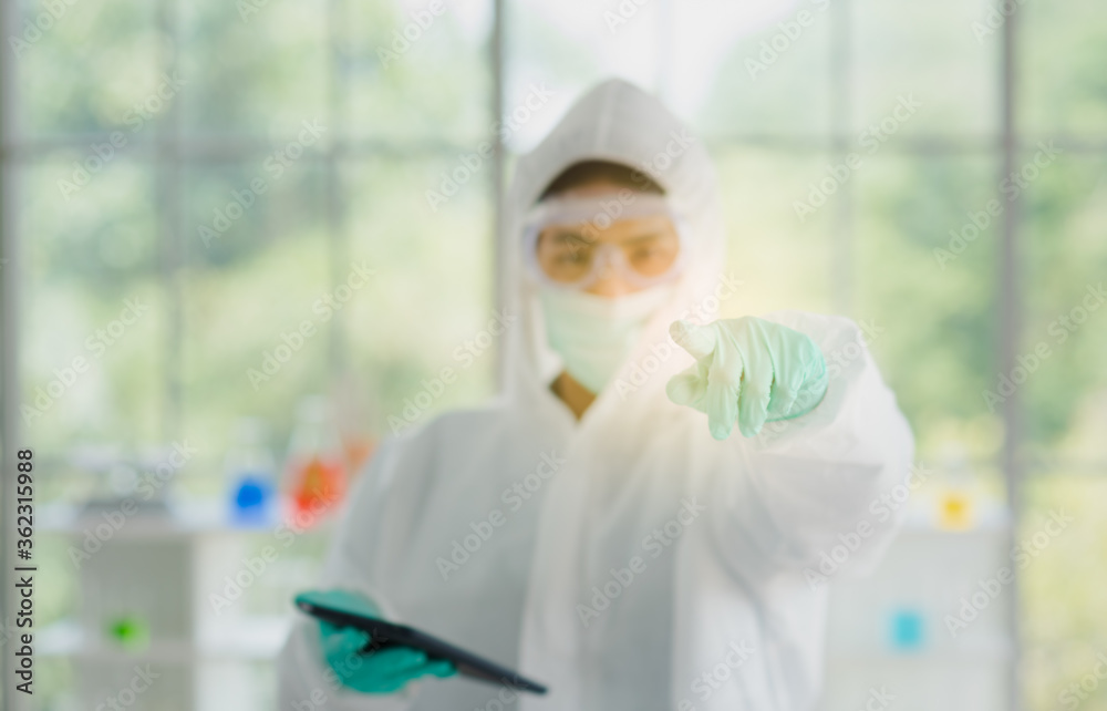 Scientist man in white sterilize lab coat wearing glasses protection and mask standing and holding tablet pointing to camera in laboratory room Scientist man in white sterilize lab coat wearing glasses protection and mask standing and holding tablet pointing to camera in laboratory room