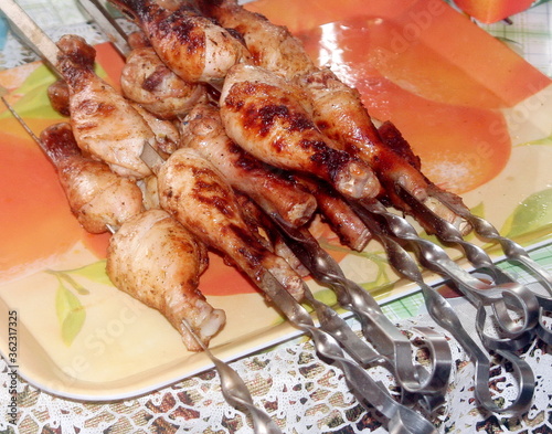 Charcoal-fried chicken legs strung on a skewer on a tray