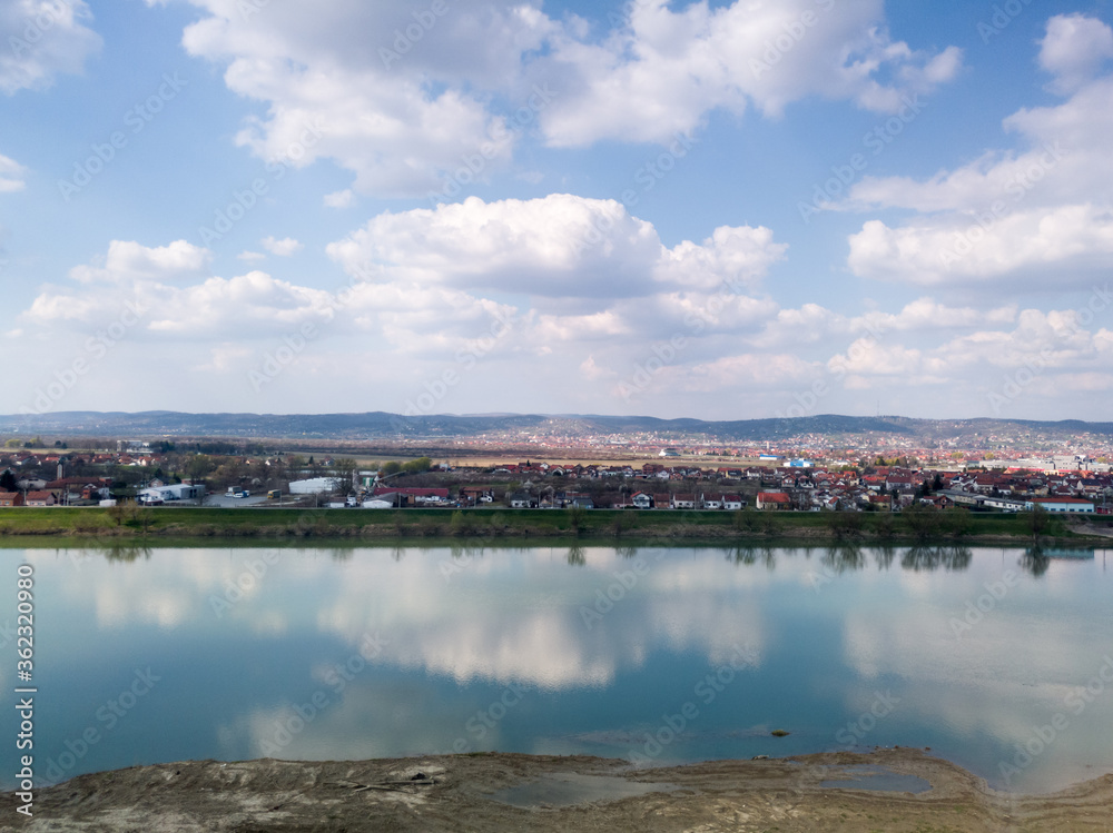Obraz premium Scenic view of Sava river and settlements around Slavonski Brod during sunny day with fluffy clouds.