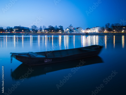 Blue hour on Sava river, promenade in Slavonski Brod and blurred boat in front. photo