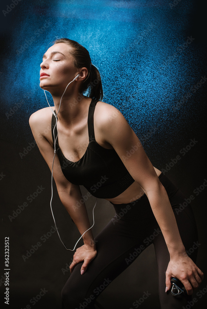 Obraz premium Slim fitness woman in black sport suit posing on black background