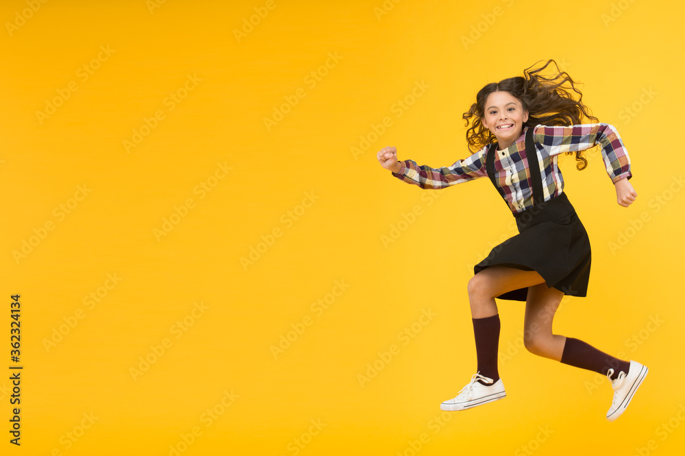 Happy childrens day. Jump concept. Break into. Feel inner energy. Girl with long hair jumping on yellow background. Carefree kid summer holiday. Time for fun. Active girl feel freedom. Fun and jump