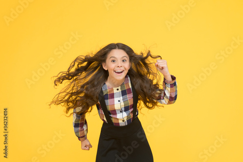 Air in her hair. natural beauty. Girl kid long hair flying in air. Child with natural beautiful healthy hair yellow background. Tips for healthy hair. Hairdresser salon. Beauty procedure. Extra light