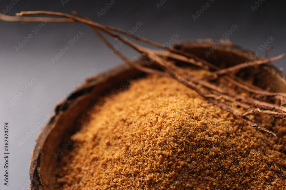 natural granulated coconut sugar in a coconut shell on a black background