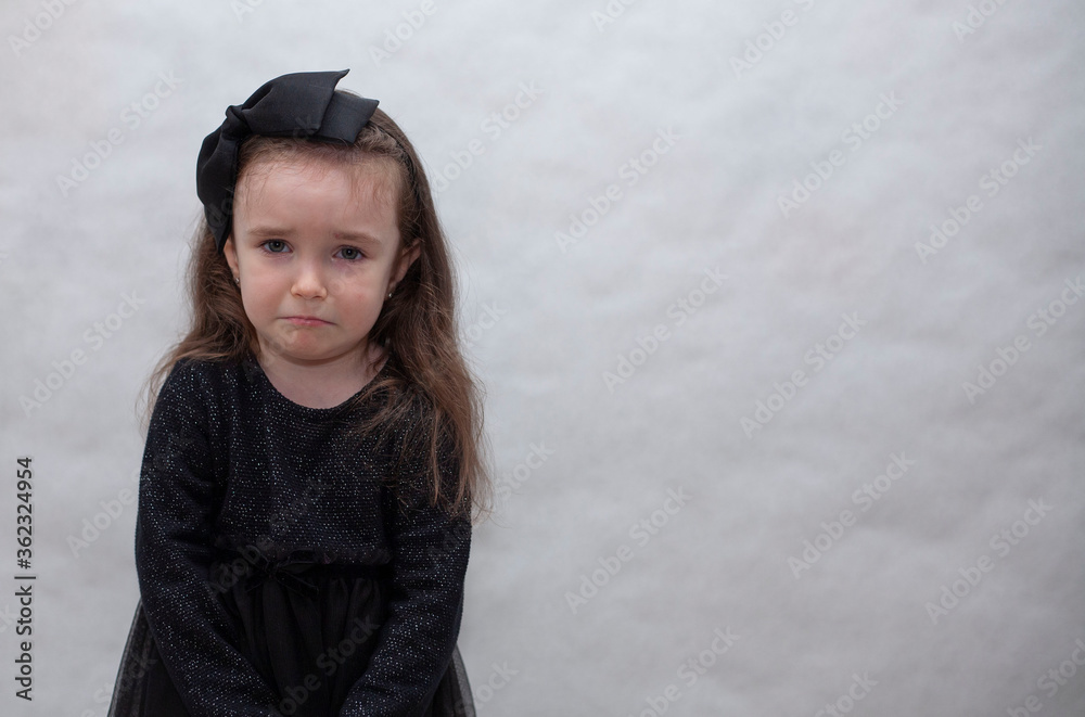 A little girl in a black dress is offended and looks at the camera A little girl in a black dress is offended and looks at the camera