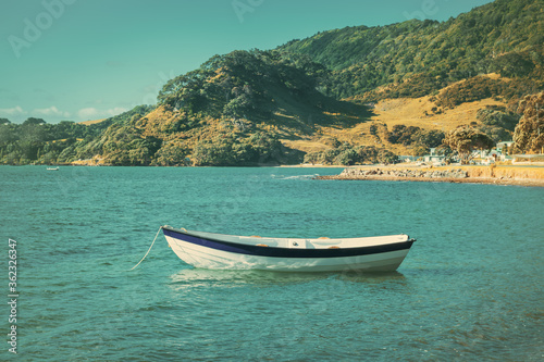 Retro-style photo of a wooden row boat moored in calm waters of the bay