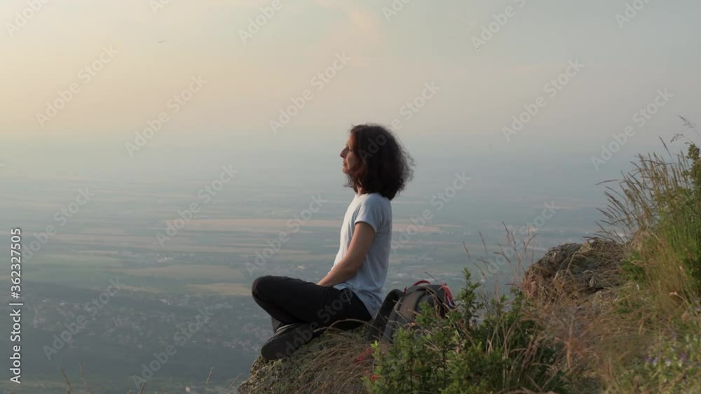 Profile of a Woman Relaxing High Above in the Mountains on the Edge of a Cliff Profile of a Woman Relaxing High Above in the Mountains on the Edge of a Cliff