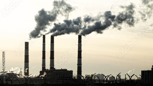 Spring, evening setting sun and smoking plant pipes. Dissonance of pure nature and polluting human activity. Save Earth concept photo