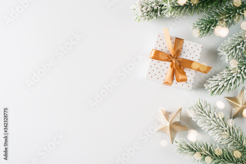 Christmas card with polka dot gift box, green branch, light, garland and stars on white background © Denira