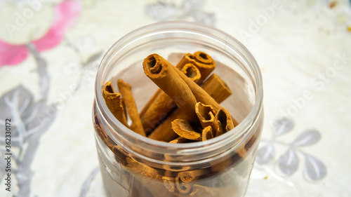 Close up detail view of cinnamon sticks in a plastic container. It is a spice obtained from the inner bark of several tree species from the genus Cinnamomum. Selective focus on foregrounds.